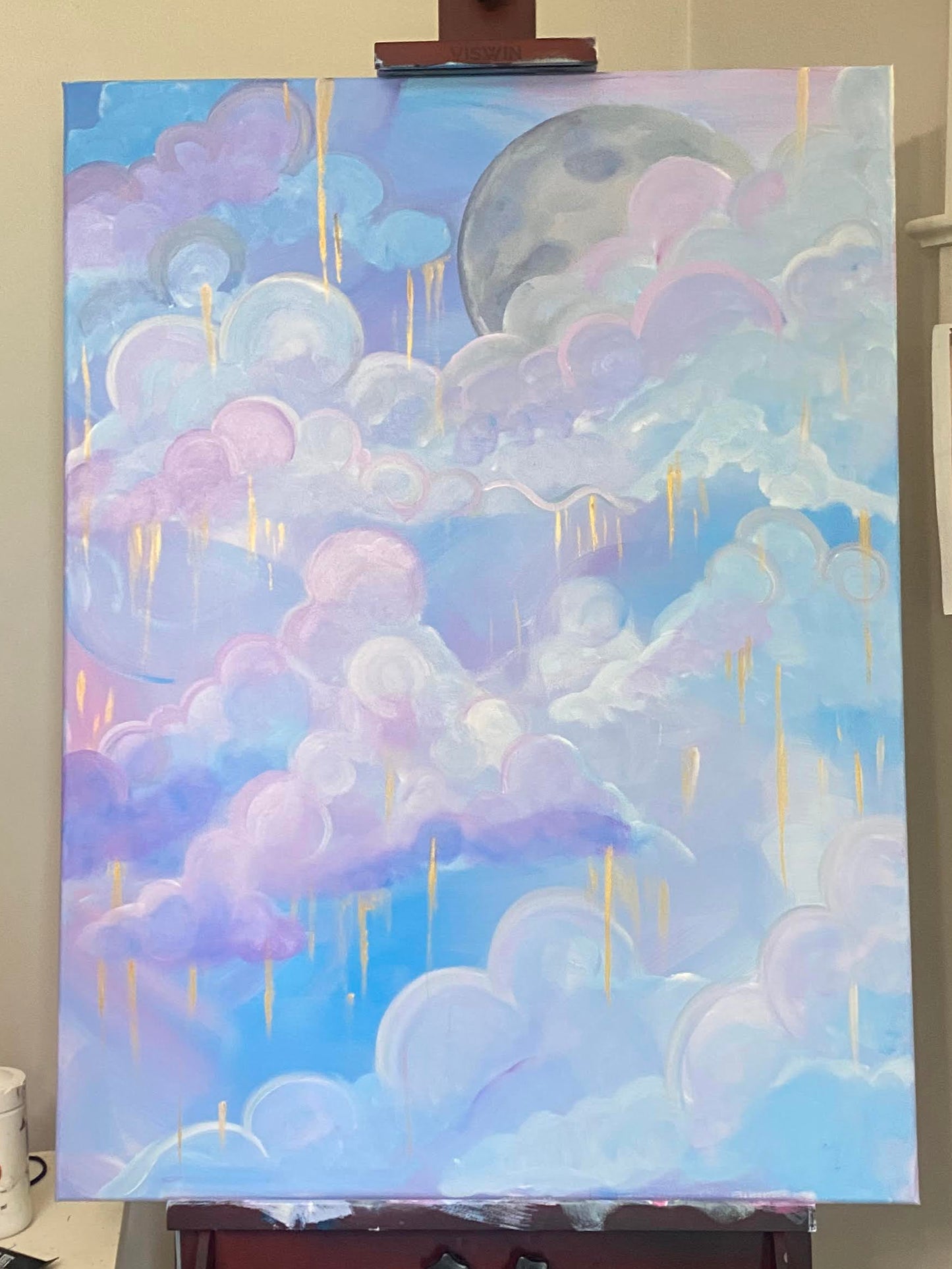 Soft clouds drift through a celestial dreamscape in Moonlit Reverie, where pastel pinks and lavenders mingle with serene blues under the watchful glow of a rising moon. Threads of gold cascade gently from the heavens, catching the light and adding a touch of the ethereal to the scene.
